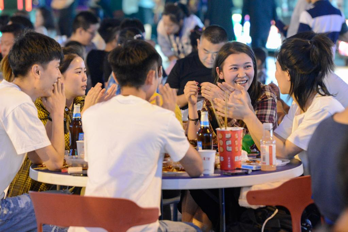 人们在乌鲁木齐市五一星光夜市上品尝美食（2019年7月5日摄）。新华社记者 丁磊 摄