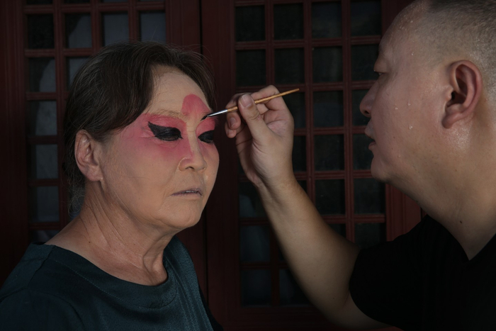 8月16日，丁石锁的徒弟邱振飞正在为“三只船”表演者化妆。新京报记者 尹亚飞 摄