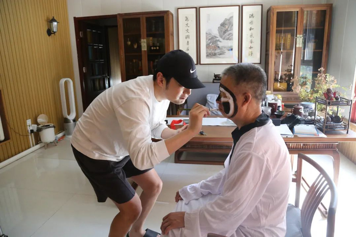 ▲陈卓在为老人化妆，扮演黑白无常。受访者供图