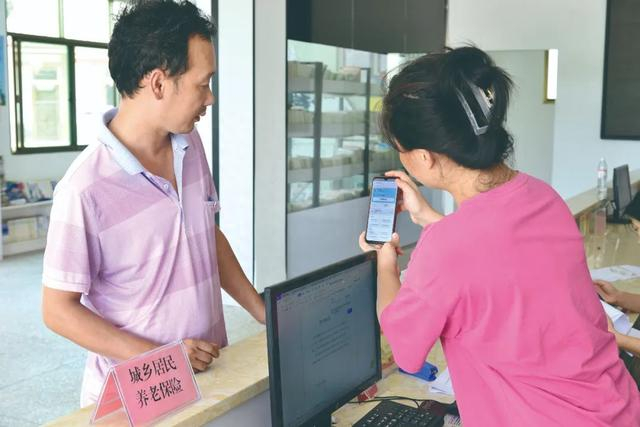 江西省兴国县长冈乡长冈村便民服务中心工作人员为办事群众办理电子社保卡申领业务。钟桂生 摄