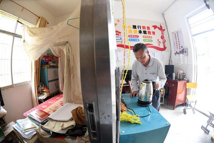　　↑龚寿新老师在办公室烧开水，办公室一墙之隔是他的卧室（2022年5月25日摄）。