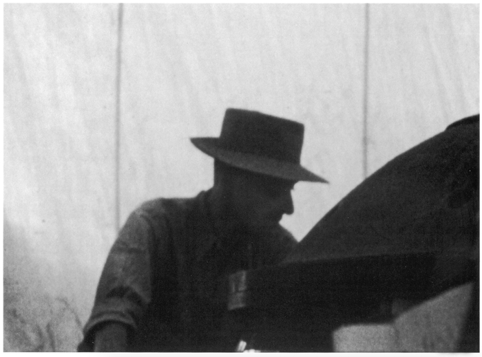 在一次测试前，戴着平顶矮帽的奥本海默在三一试验场的塔架上俯身查看“小装置”。图源：《奥本海默传》