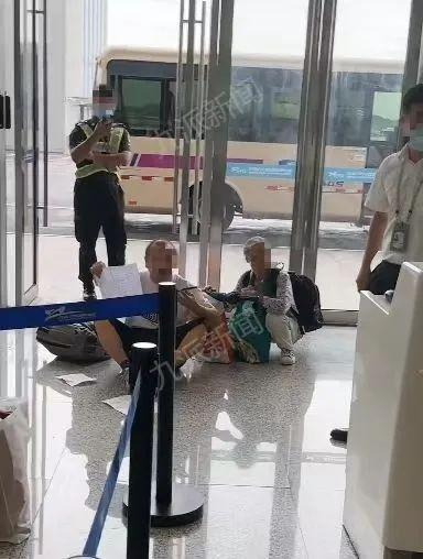 男子与老太坐在地上与工作人员沟通。视频截图