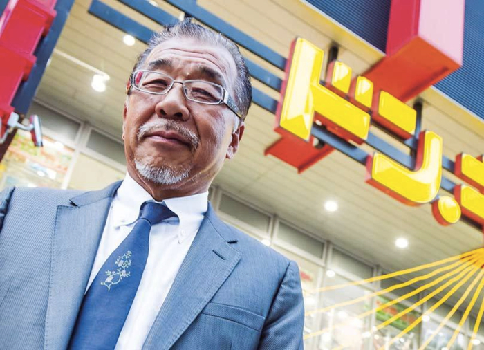 ▲安田隆夫，背景是一家“唐吉诃德”百货。