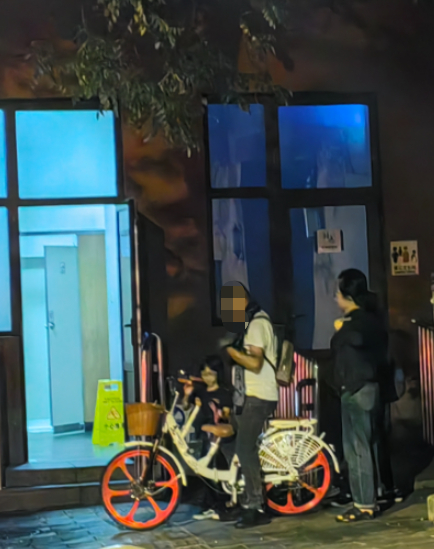 游客从公厕旁角落取出刚租赁的亲子车。