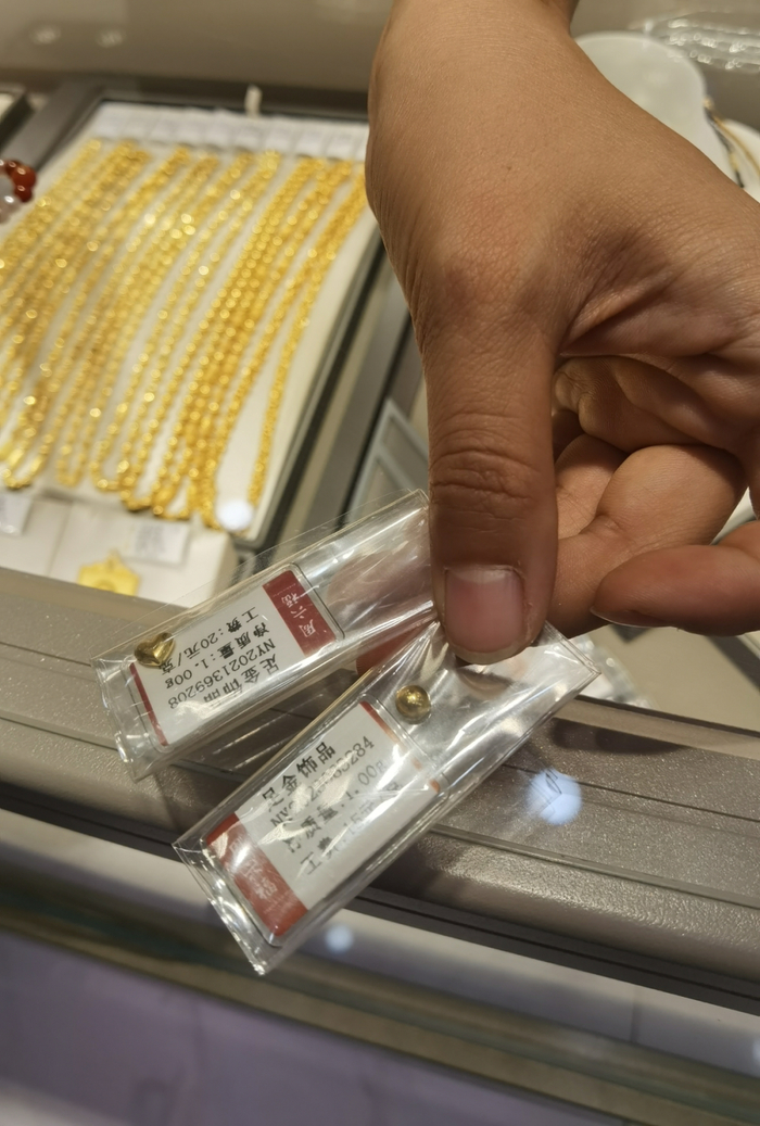 图为一门店销售人员展示金豆产品。 新华社记者 马晓媛 摄