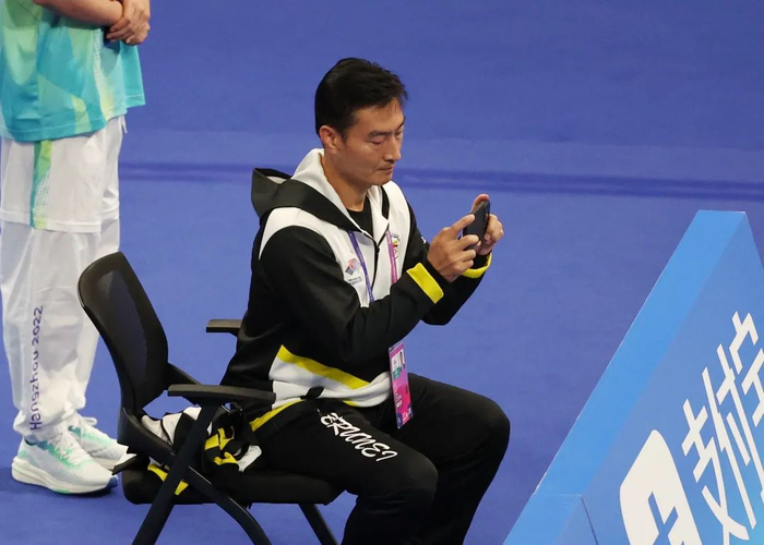 ▲李辉在场边给比赛中的文莱运动员拍照片。新京报记者 王贵彬 摄