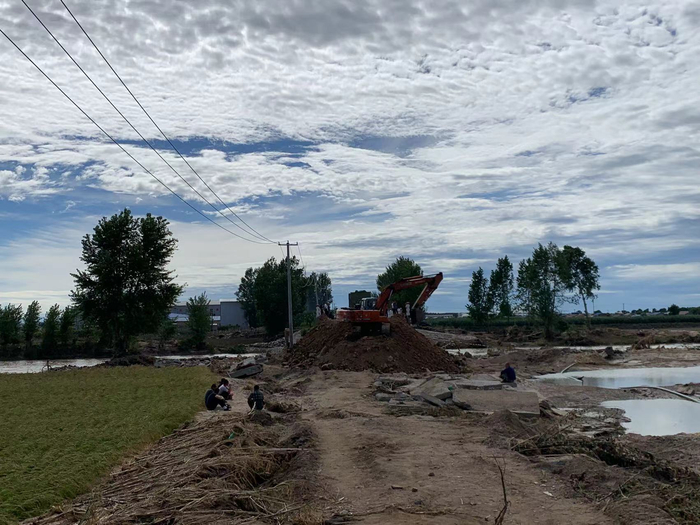 村民们在等被冲垮的桥修好。高佳摄