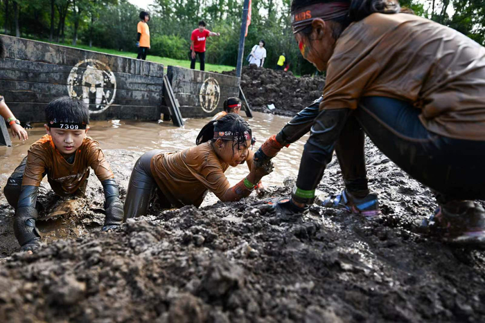 北京世园公园旅游度假区，参与斯巴达勇士儿童赛北京站的少年们携手越过障碍。北京世园公园供图