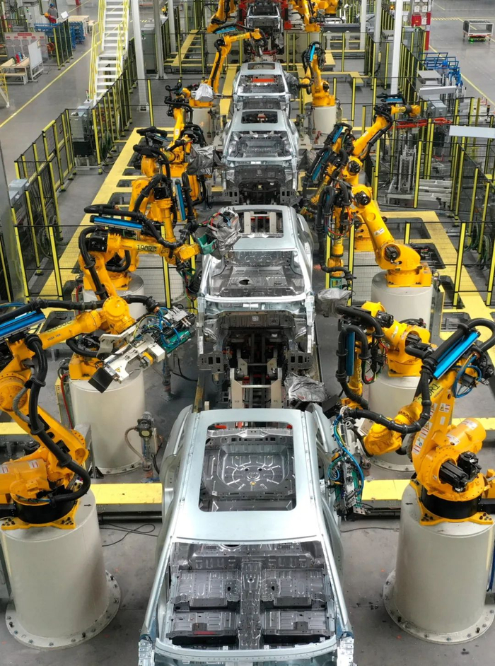 在山东青岛市一家汽车制造企业的焊装车间，机器人在进行焊接作业（无人机照片）。新华社发