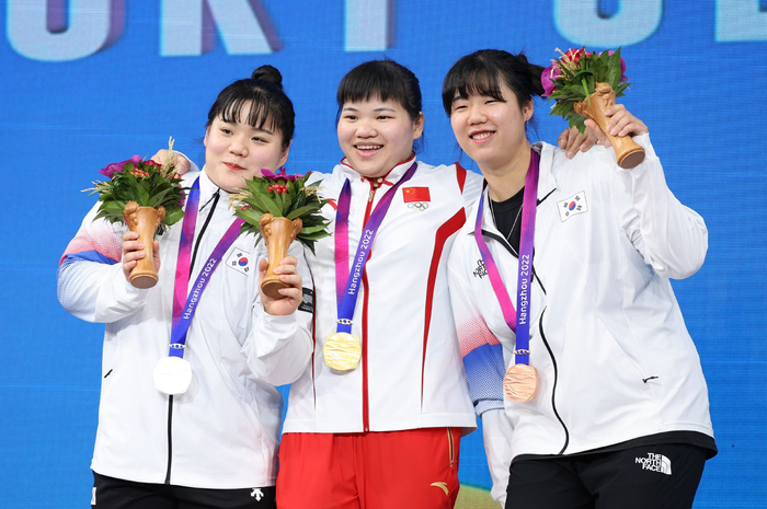 中国女举唯一的亚运金牌来自梁小梅（中），她击败两名韩国选手，获得女子87公斤级金牌。  图/新华社