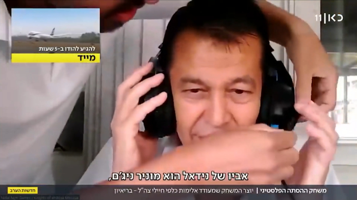 尼达尔为父亲戴上耳麦接受采访