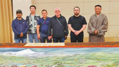 呷绒翁都（右一）与俄罗斯列宾美术学院艺术家等在《香巴拉画卷》前合影。四川日报全媒体记者 田为 摄