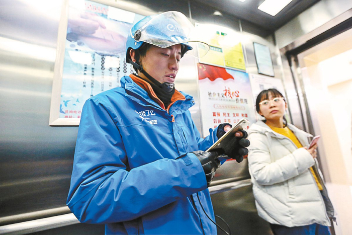 一名外卖员在电梯里不停地刷着手机抢单