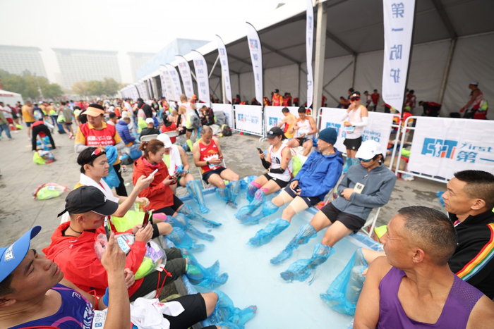 2023年10月29日，奥林匹克公园景观大道，完赛后的运动员正在拉伸区域外泡脚放松。新京报记者 王飞 摄