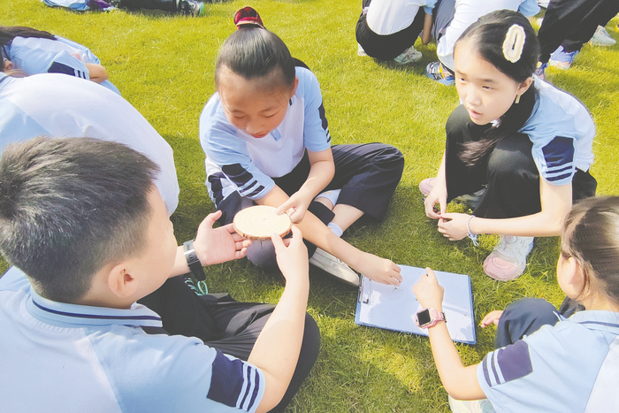     ▲研学活动中，南宁市银杉路小学学生通过树木年轮的宽窄了解气候变化、辨别方向。 （学校供图）