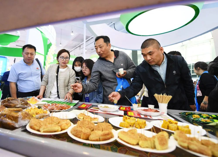 4月10日，参观者在河南省新乡市开幕的中原农谷预制菜国际博览会上品尝加工好的预制食品（张浩然/摄）