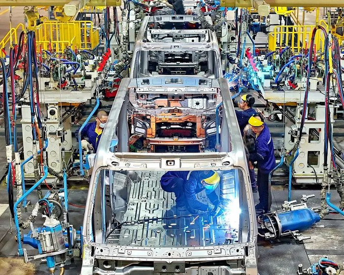 10月9日，江西省一家商用新能源汽车生产企业冲焊车间内，工业机器人快速运转。