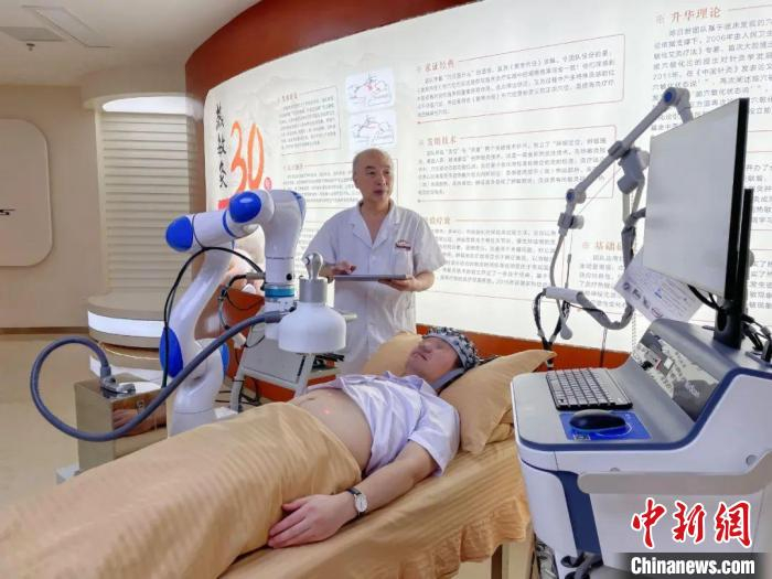 图为江西中医药大学附属医院陈日新教授正在用热敏灸机器人为患者治疗