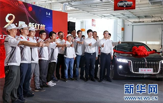 2020年7月9日， 在长春市红旗工厂焊装车间内，工人与一辆红旗H9合影。
