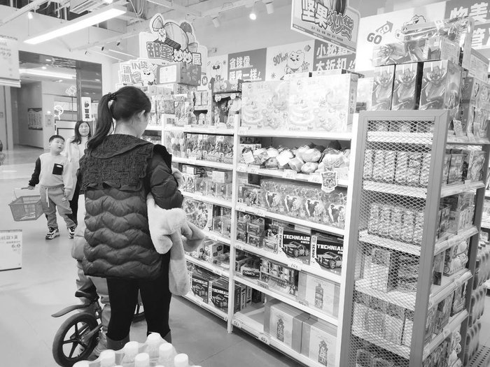 　　▲　图为市民带孩子在品牌零食店里选购。