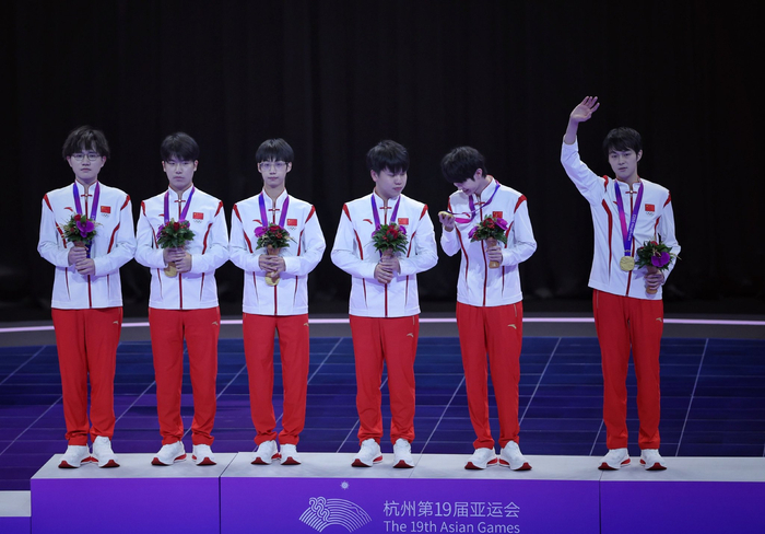 杭州亚运会，中国队夺得王者荣耀项目冠军，孙麟威（左一）和俱乐部队友罗思源（左二）登上领奖台。  新京报记者 薛珺 摄