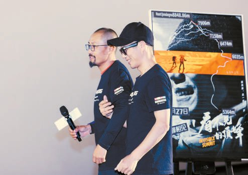 《看不见的顶峰》全国首映礼上，张洪与向导强子走过海报。 IC photo供图
