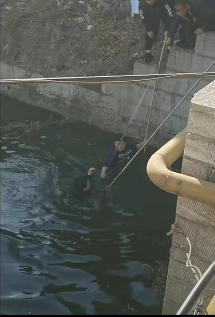 12月2日，赵宏伟（穿蓝色毛衣者）拉住绳子，下水救人。 图源：视频截图