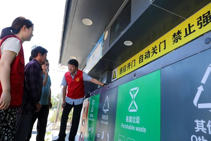 　　在安徽省合肥市长丰县庄墓镇枣林社区，志愿者指导居民使用智能垃圾分类回收设备（2023年9月1日摄）。新华社记者 曹力 摄