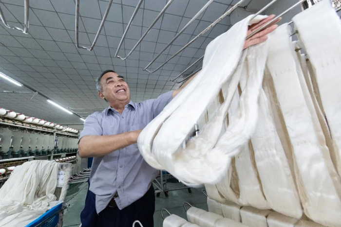 苏州市吴江区盛泽镇一家纺织工厂员工将浸泡过的白厂丝晾干用于捻线（2023年5月11日摄） 蒋文超摄