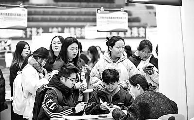 11月18日，江苏省淮安市，大学生在校园招聘会上挑选工作岗位。赵启瑞摄/光明图片