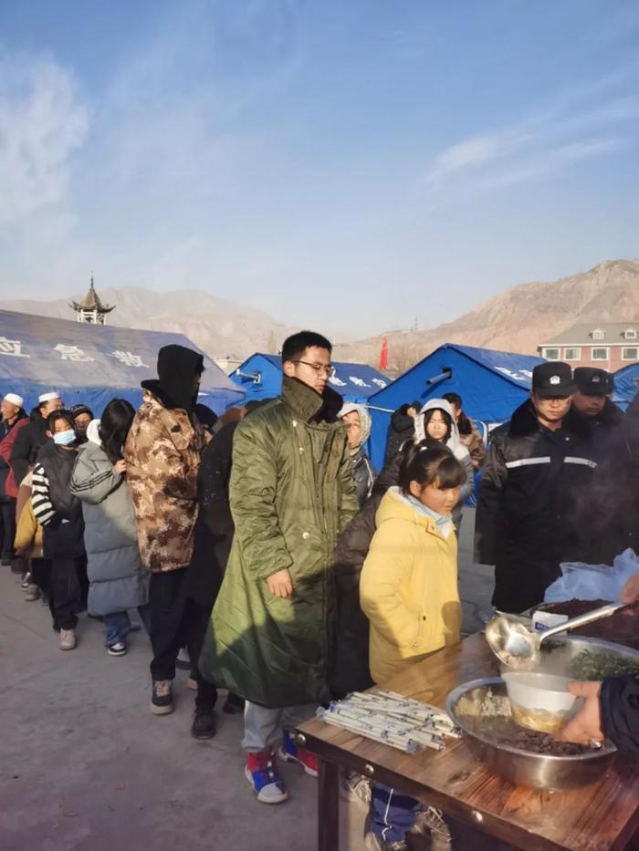12月21日,积石山县大河家镇安置点,高三学生张玉海在列队取餐。中青报·中青网记者 尹海月/摄