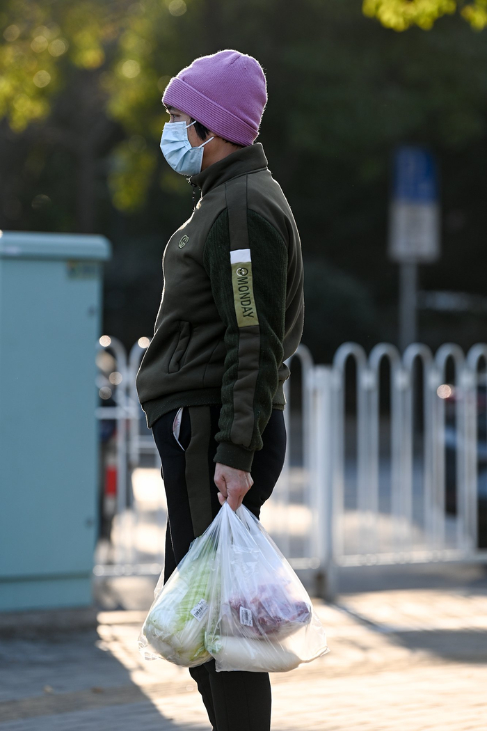 2023年12月21日，上海，市民穿着厚衣服，戴着帽子出门买菜。