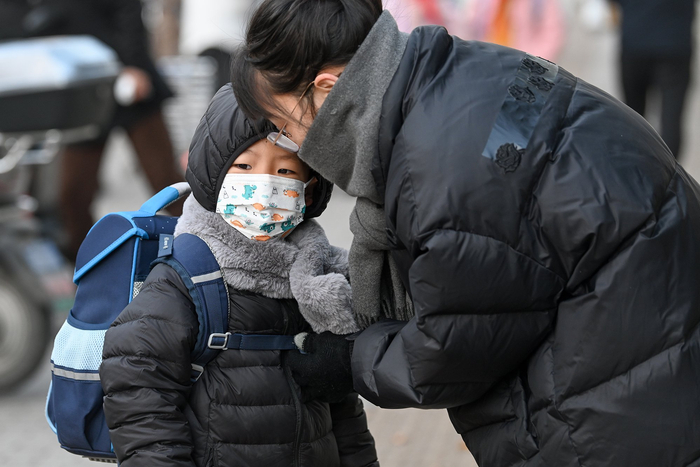 2023年12月21日，上海，家长带着裹得严严实实的小朋友去上学。