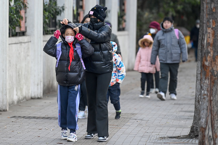 2023年12月21日，上海，家长带着裹得严严实实的小朋友去上学。