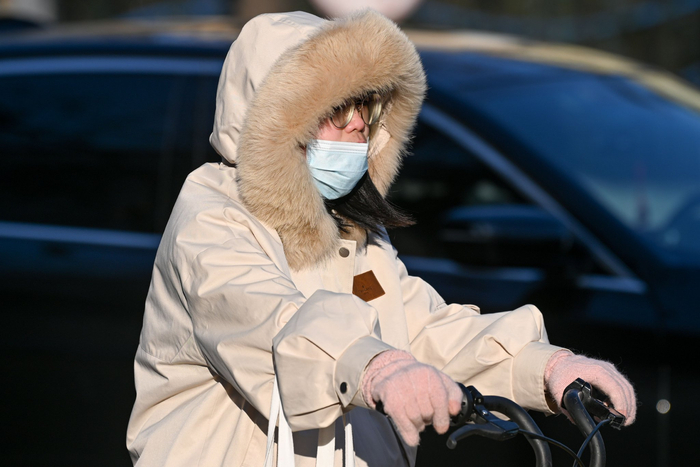 2023年12月21日，上海，市民穿着羽绒服，戴着手套骑车出行。