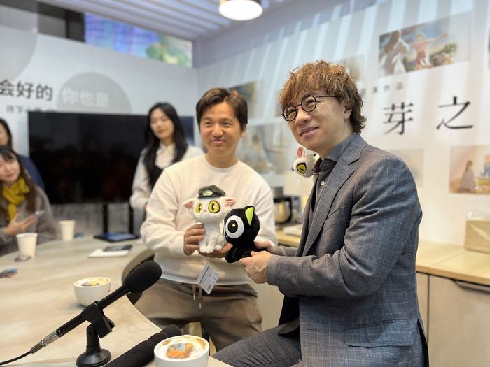 《罗小黑战记》导演木头（中）和新海诚合影。澎湃新闻记者 陈晨 图