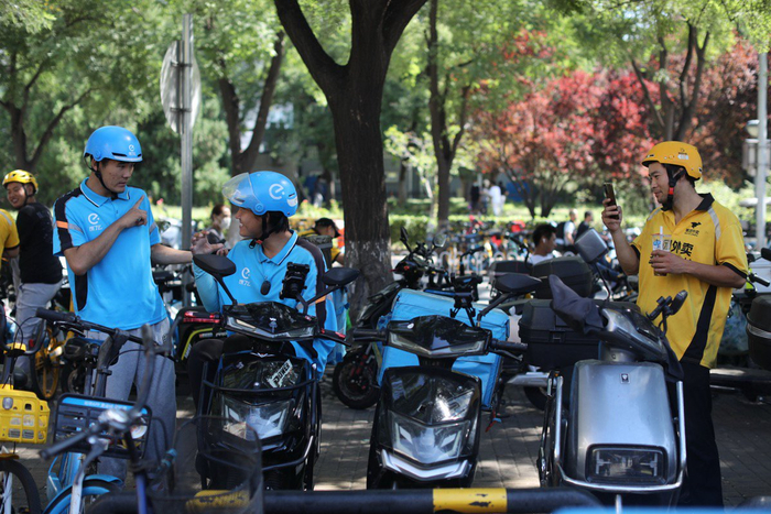 刘一飞（图中）和同站点的另一名听障骑手交流。