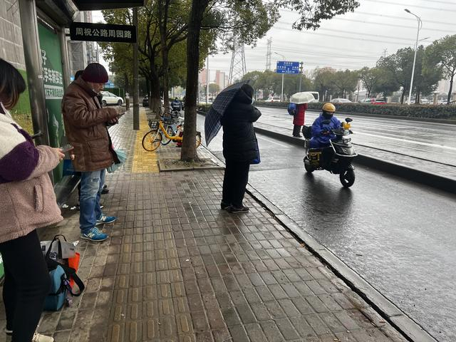 12月19日，在公交站台等车的人，需要穿过一段非机动车道才能上车。王昀 图