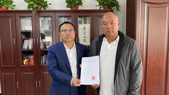     周永刚（右）和律师孙阔手拿再审出庭通知书。受访者供图