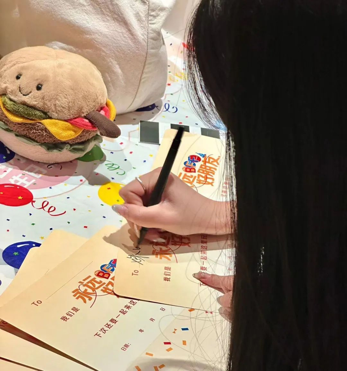 飞飞在给朋友们手写邀请函。（图/受访者供图）