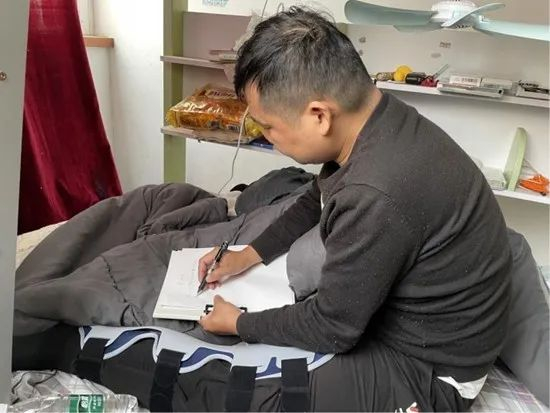 向建军坐在租屋的床上写材料。受访者供图