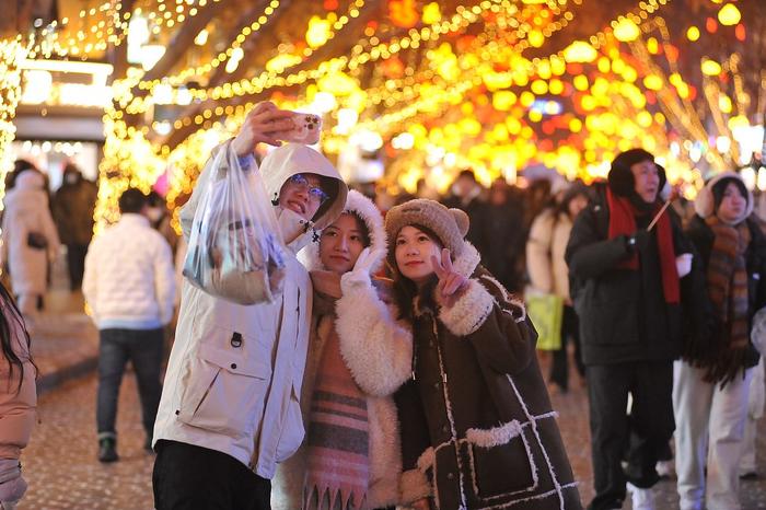 2023年12月31日晚，哈尔滨，游客们在中心大街，赏花灯，观瞧欧式建筑，打卡网红景点。