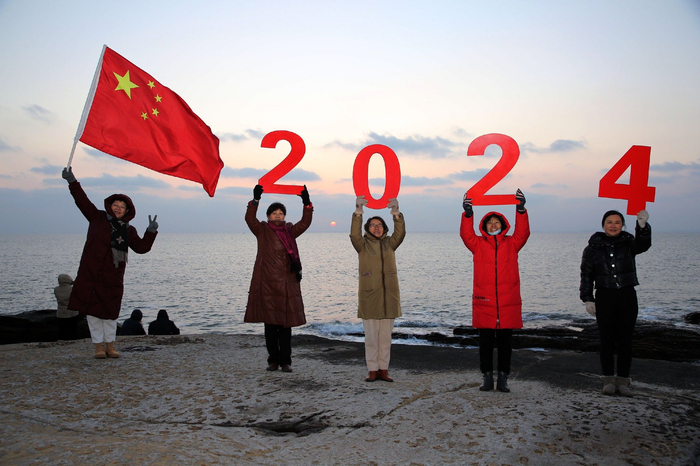 2024年1月1日，江苏连云港，游客手举五星红旗，摆出“2024”造型迎接新年。IC photo 图