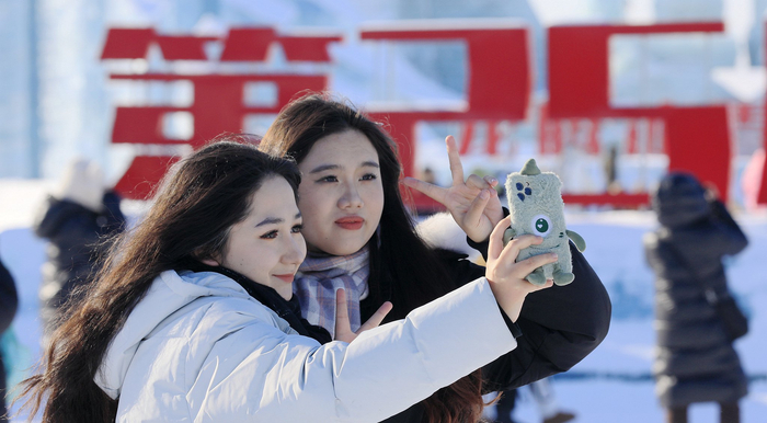 2023年12月31日，哈尔滨，游客在冰雪大世界园区自拍。视觉中国 图