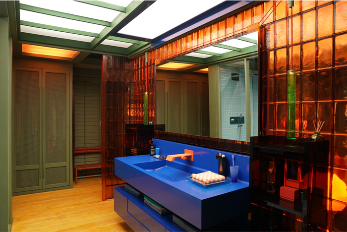 用一面橙色的玻璃墙隔开，一边是蓝色的床铺，另一边则是同样蓝色的盥洗台