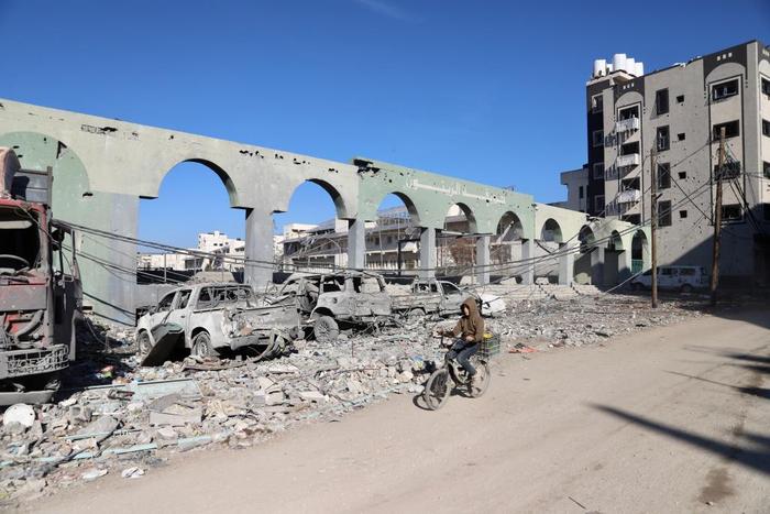 ▲1月7日，巴勒斯坦人骑车经过加沙城的内访建筑废墟。图/新华社