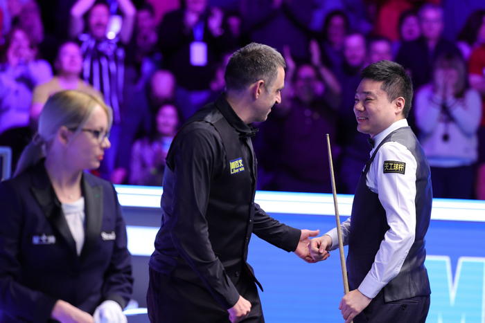 打出满分杆后，丁俊晖接受奥沙利文（中）的祝贺。  图/新华社