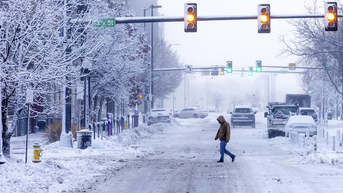 当地时间2024年1月9日，美国内布拉斯加州奥马哈市，一名行人在暴风雪中穿过街道。