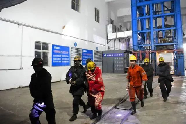 1月13日，救援人员与几名被困矿工升井后走出。图源：新华社